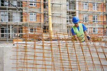 Fototapeta premium Construction worker and reinforced concrete, building at the construction site
