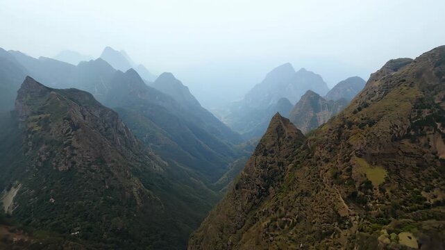The mountains are covered in trees and the sky is cloudy. The mountains are very tall and the trees are green