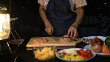 A woman prepares ingredients and prepares BBQ. Grilling for the party in the night. A woman is getting ingredients ready and grilling BBQ for a party at night.