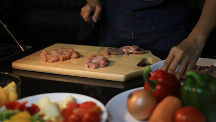 A woman prepares ingredients and prepares BBQ. Grilling for the party in the night. A woman is getting ingredients ready and grilling BBQ for a party at night.