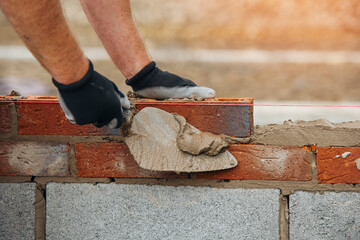 Construction Worker Placing Brick in Mortar Using Trowel