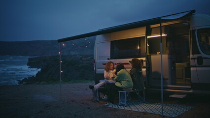 Fototapeta premium Friendly company relaxing camping terrace in evening seashore. Women talking