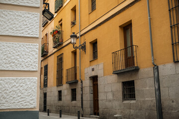 Old narrow street downtown of Madrid with vintage buildings with small balconies decorated with...