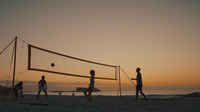 Summer games: Four silhouetted beach volleyball players on the court at sunset