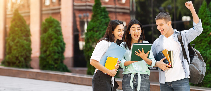 Pass exams. Joyful university students reading test results standing in college campus, celebrating success
