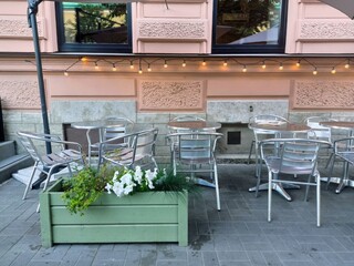  Summer cafe on the street with metal tables and chairs decorated with garlands