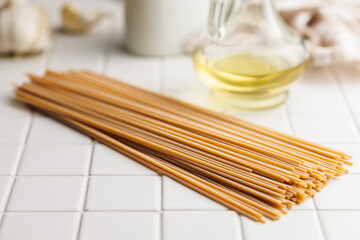 Uncooked whole grain pasta. Raw spaghetti on tile table.