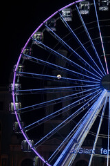 Illuminated Ferris wheel at night with colorful lights