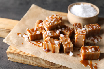 Tasty candies, caramel sauce and salt on grey table, closeup