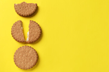 Tasty sandwich cookies on yellow background, top view. Space for text