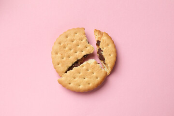Piece of tasty sandwich cookie on pink background, top view