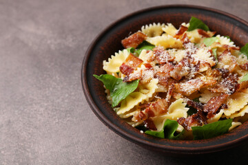 Tasty pasta with bacon and basil on brown table, space for text