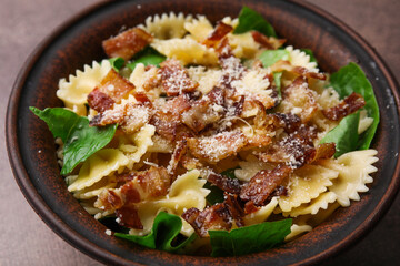 Tasty pasta with bacon and basil on brown table, closeup