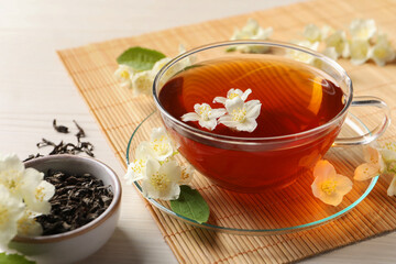 Hot jasmine tea in cup and flowers on white wooden table