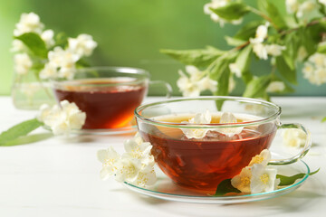 Hot jasmine tea in cup and flowers on white marble table