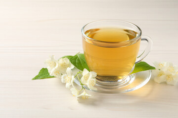 Hot jasmine tea in cup and flowers on white wooden table