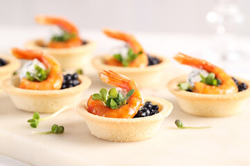 Delicious canapes with shrimps and black caviar on table, closeup