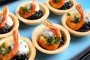 Delicious canapes with shrimps and black caviar on plate, closeup