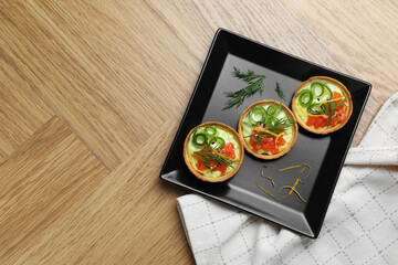Delicious canapes with salmon on wooden table, top view. Space for text