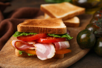 Tasty sandwich with bacon and tomato on table, closeup