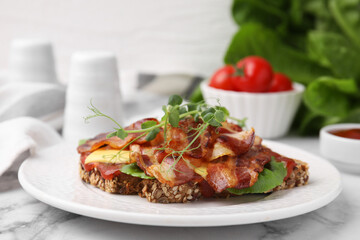 Tasty sandwich with bacon and microgreens on white marble table, closeup