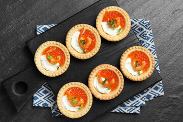 Delicious canapes with shrimps, red caviar and cream cheese on dark textured table, top view