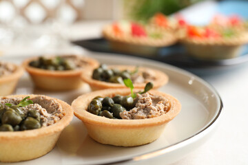 Delicious canapes with pate and capers on white table, closeup
