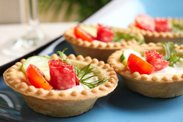 Delicious canapes with dry smoked sausages, cream cheese and vegetables on table, closeup