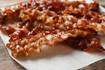 Slices of tasty fried bacon on wooden table, closeup