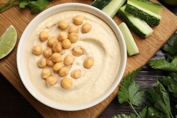 Tasty hummus with chickpeas in bowl and fresh products on wooden table, flat lay