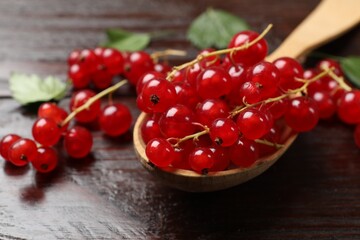 Fresh red currants in spoon on wooden table, closeup