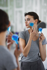 A young woman is doing a relaxing face massage using cold cryo spheres.