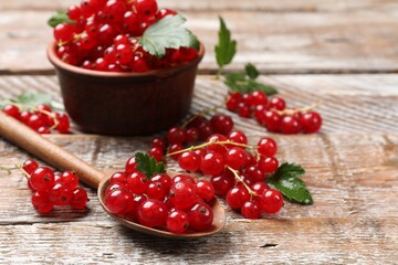 Fresh red currants and green leaves on wooden table, closeup