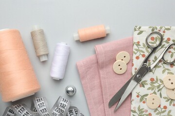 Flat lay composition with different sewing supplies on light grey background
