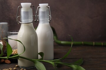 Different types of vegan milk and ingredients on wooden table