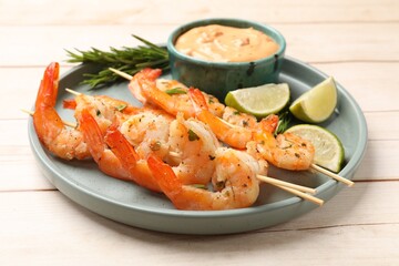 Skewers with delicious grilled shrimps served on white wooden table, closeup