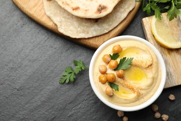 Delicious hummus with olive oil and chickpeas served on grey textured table, flat lay. Space for...