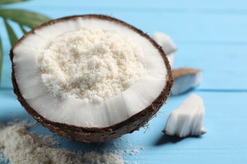 Fresh coconut flour in nut on light blue wooden table, closeup