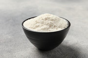 Coconut flour in bowl on light grey table, closeup