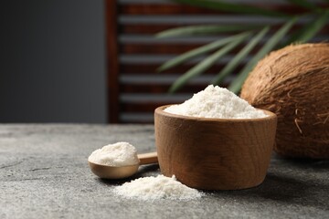 Organic coconut flour in bowl, spoon and fresh fruits on grey table. Space for text