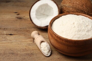 Coconut flour in bowl, scoop and fresh fruits on wooden table, closeup. Space for text