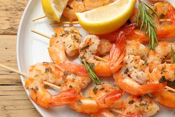 Skewers with delicious grilled shrimps served on wooden table, top view