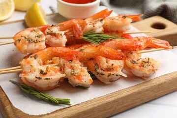 Skewers with delicious grilled shrimps on white table, closeup