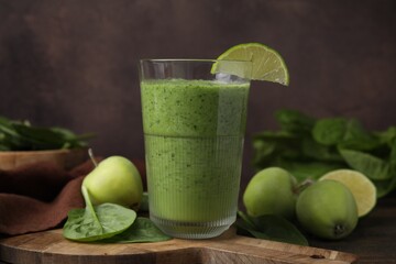 Tasty green smoothie in glass with lime, apples and spinach on wooden table, closeup