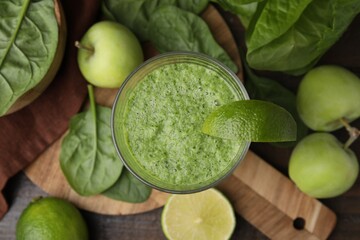 Tasty green smoothie in glass with lime, apples and spinach on wooden table, flat lay
