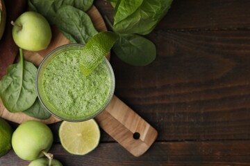 Tasty green smoothie in glass with lime, apples and spinach on wooden table, flat lay. Space for text