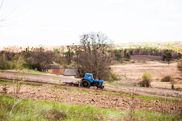 Blue Tractor Plowing a Field in Rural Landscape