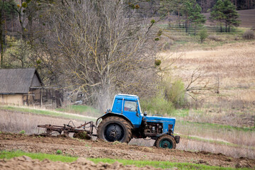 Blue Tractor Plowing Field in Rural Landscape