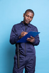 African american security agent takes notes on files to keep evidence of responsibilities while he...