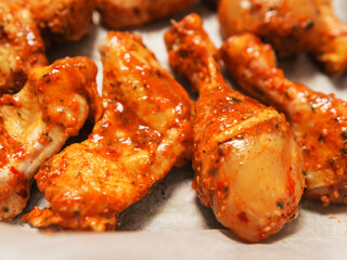 Asian style marinated chicken drumsticks and wings on cooking paper in a metal tray ready to be cooked. Fine poultry product for oven or barbecue. Simple popular traditionally meal.